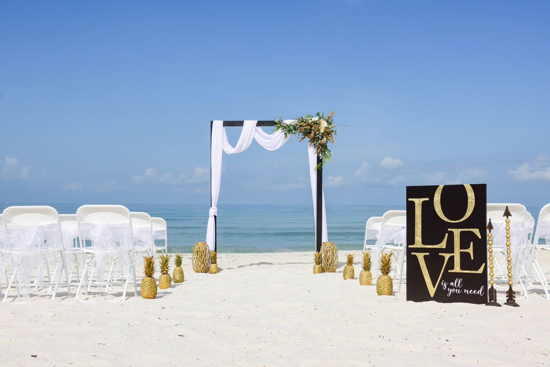 Beach wedding setup with chairs, an arch, and