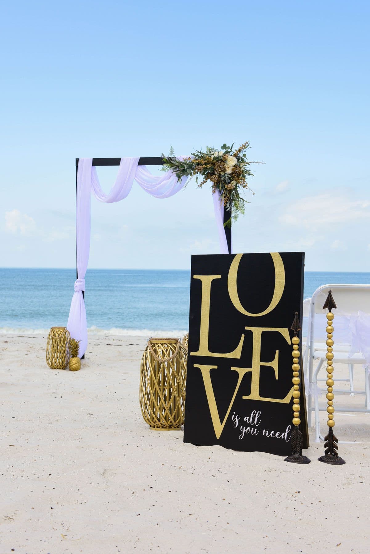 Wedding arch and sign on a beach. Black and gold