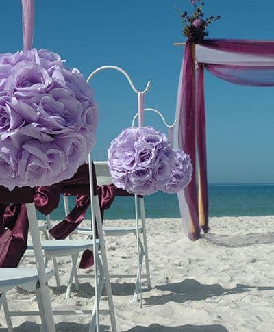 Purple flowers decorating a beach wedding arch