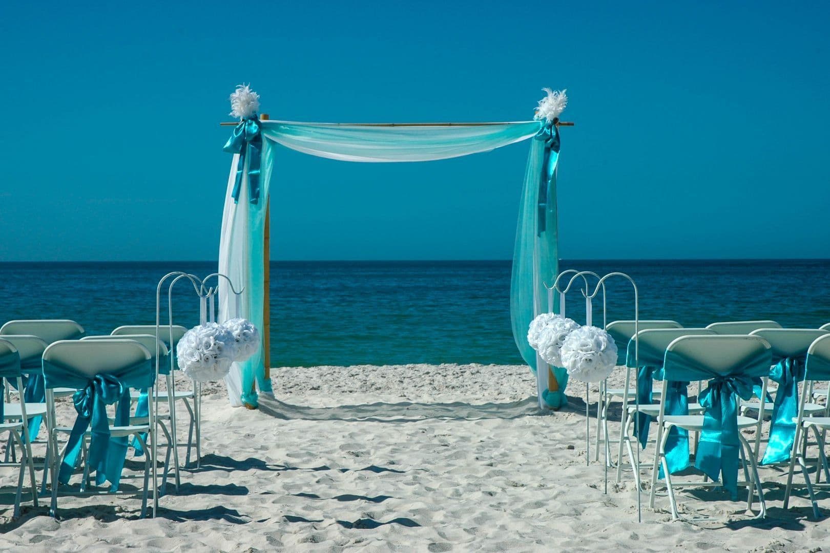 Bamboo canopy with turquoise and white draping and white floral pomanders on a Florida beach